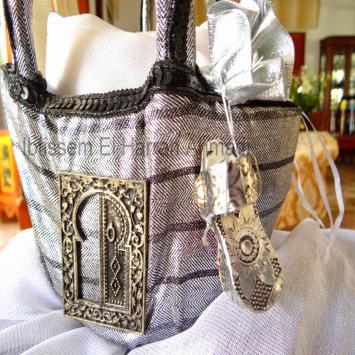 Notre pac de hamman a 5 pièces :  nous avons la Fouta ,un savons  dans une petite bourse en organza , un gant de toilette Kessa  attaché avec une khômsa en métal argenté ,un petit pot en céramique,une petite bourse en tissu argenté avec dedans du 